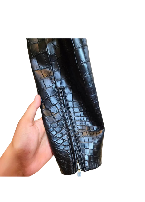 Hand holding a black crocodile-patterned clutch bag 