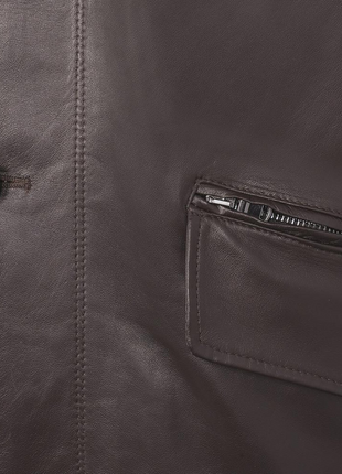 Close-up of a brown leather jacket with a button and zipper pocket.