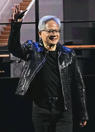 Man in a shiny black jacket waving on a stage